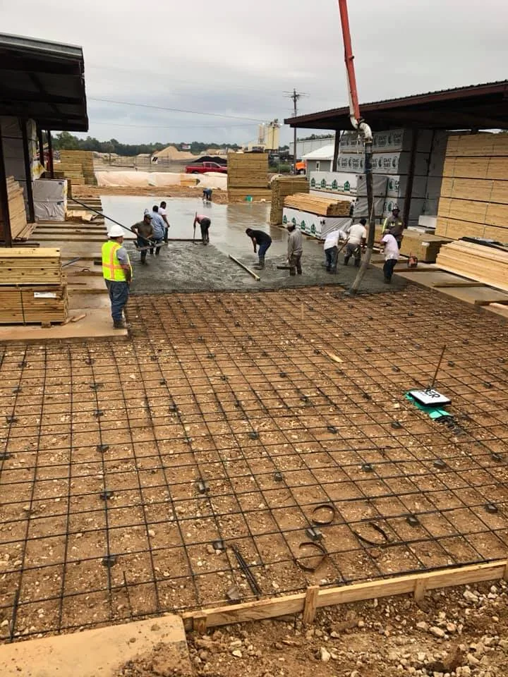 Crew placing concrete over reinforcing mesh inside a building